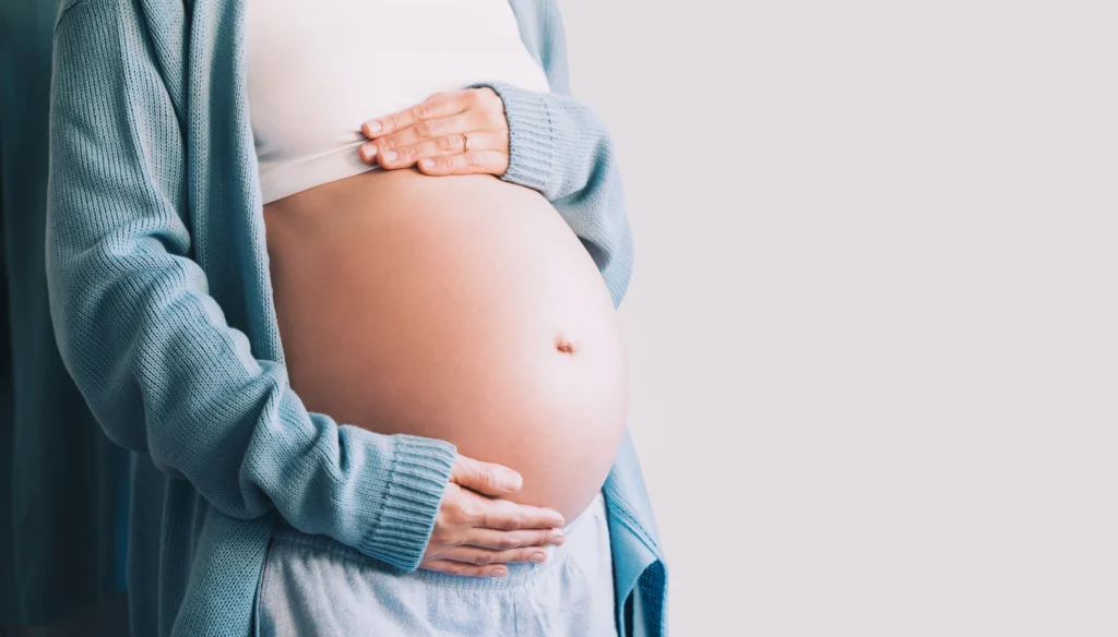 Pregnant woman holds hands on her belly. Pregnancy, maternity, preparation and expectation concept. 